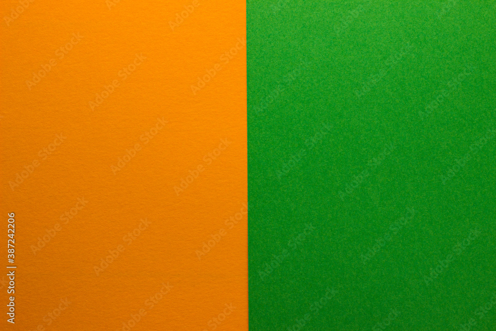 Fototapeta premium Background of two vertical rectangles green and orange. Sheets of blank green and orange paper with fine texture, split vertically, close up.
