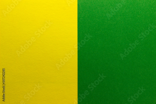 Background of two vertical rectangles yellow and green. Sheets of blank yellow and green paper with fine texture  split vertically  close up.