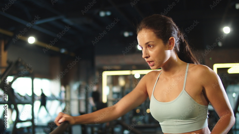 Cute fitness woman training at gym. Fit girl using velosimulator in sport club
