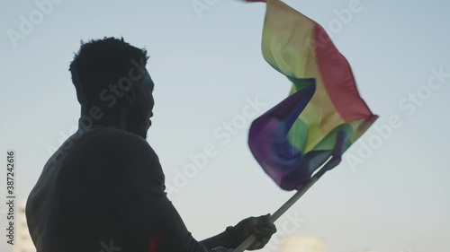 Black man waving rainbow flag. Sexual identity and equal treatmant concept. High quality 4k footage photo