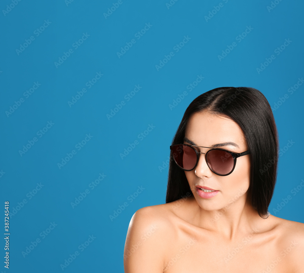 Beautiful woman wearing sunglasses on blue background. Space for text Beautiful woman wearing sunglasses on blue background. Space for text