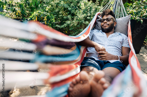 Obraz na plátně Black man napping in hammock in back yard