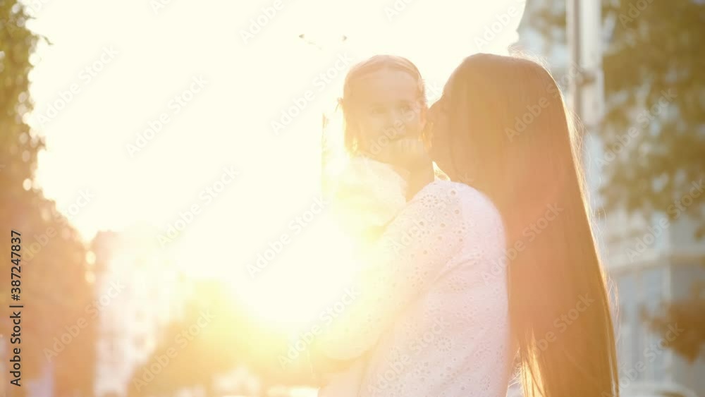 Family spending time together. The loving mother is holding her daughter and having fun with her ourside in a city. Love relationship. Family spending time together. The loving mother is holding her daughter and having fun with her ourside in a city. Love relationship.