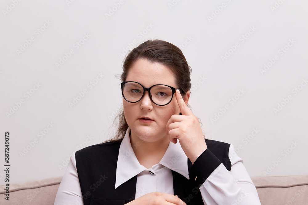 A young woman with black-rimmed glasses looks at the camera. Plus size model. A young woman with black-rimmed glasses looks at the camera. Plus size model.