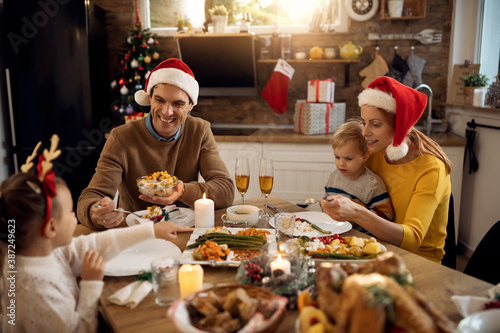 Happy parents and their children having lunch while celebrating Christmas at home.