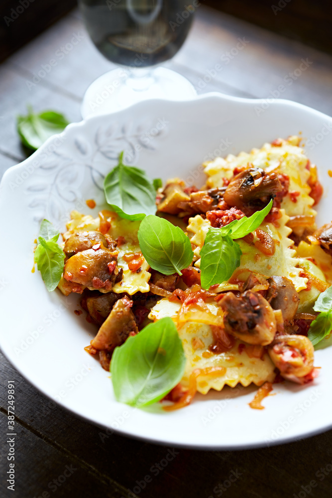 Ravioli with mushrooms and fresh basil. Dark wooden background. Close up