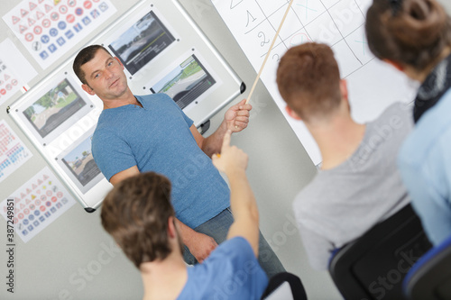 driving instructor pointing at board in a classroom