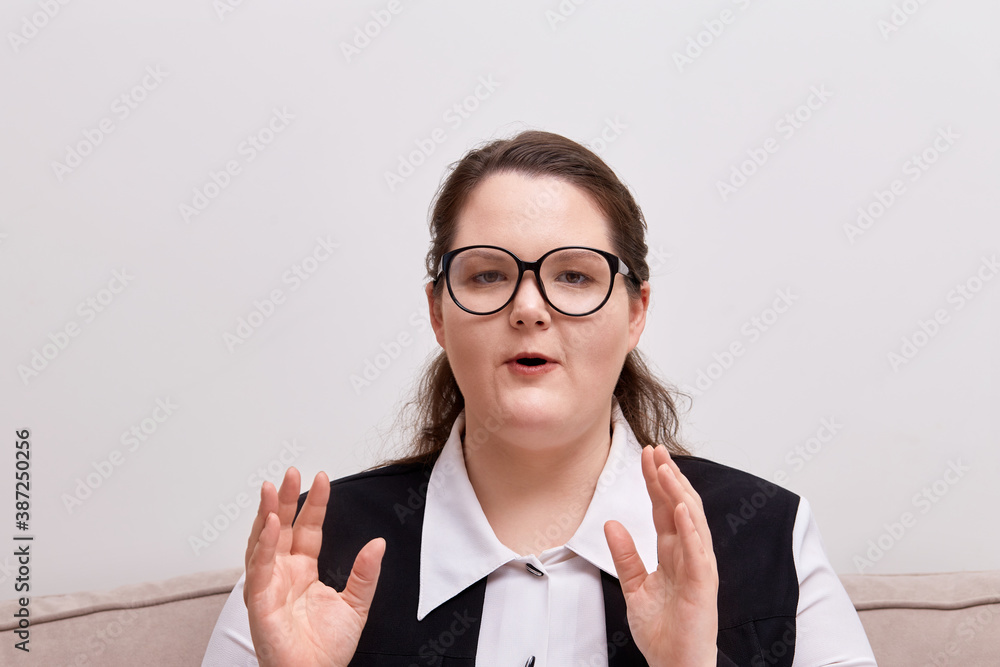 Young beautiful woman plus size model in black-rimmed eyeglasses, looks at the camera and says. Young beautiful woman plus size model in black-rimmed eyeglasses, looks at the camera and says.