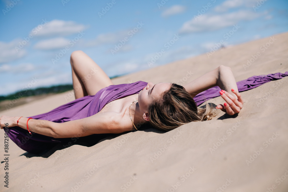 Young, slender girl with purple cloth poses in the desert Young, slender girl with purple cloth poses in the desert