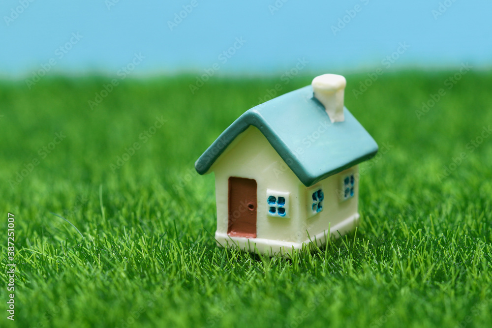 Small toy house on a background of grass and sky. Small toy house on a background of grass and sky.