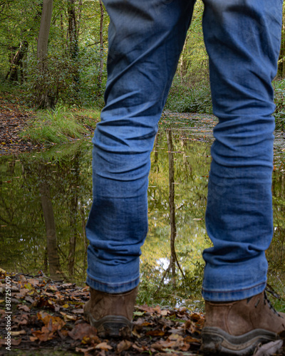 Person standing in front of lake in forest 