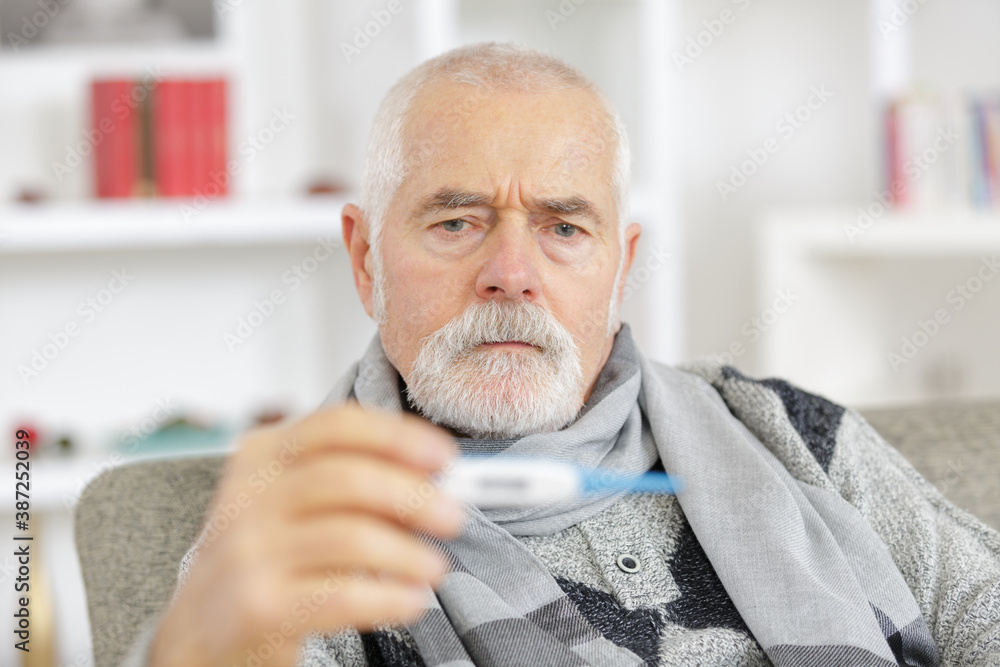 sick senior man in scarf holding thermometer at home - obrazy, fototapety, plakaty 