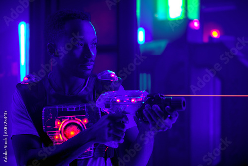 laser tag player holding gun shooting light in black light labyrinth
