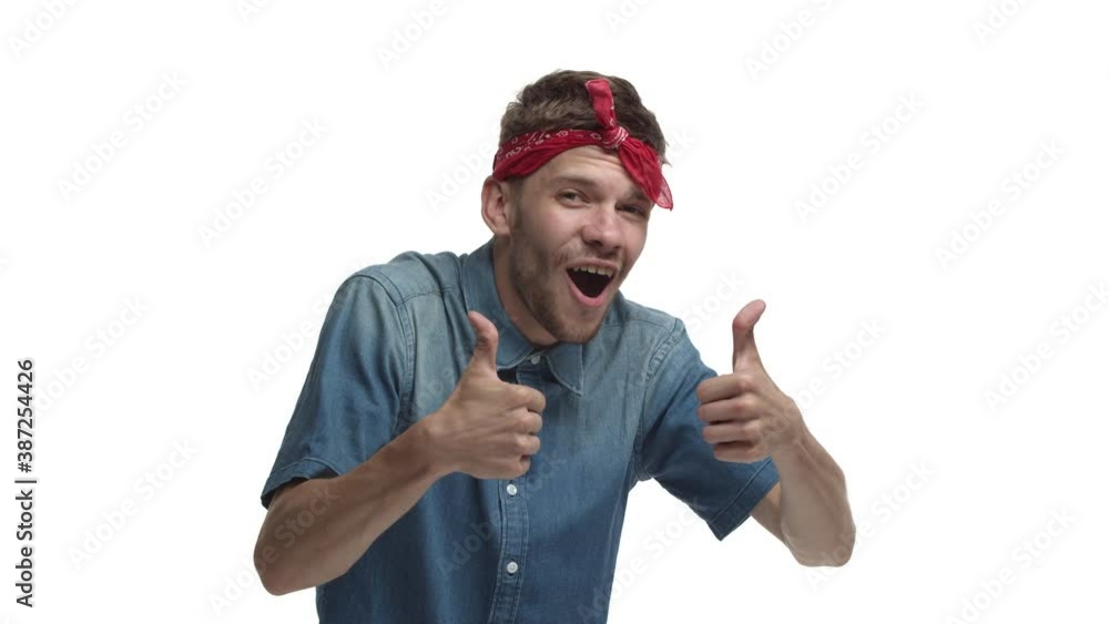 Cheerful handsome man with red headband over forehead, showing thumbs-up in approval, praise you and making compliment, standing pleased over white background Cheerful handsome man with red headband over forehead, showing thumbs-up in approval, praise you and making compliment, standing pleased over white background