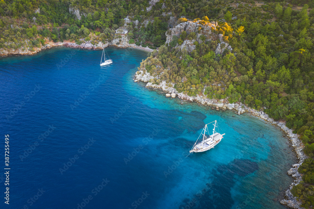 Obraz premium aerial view to curved bay with two sailing yachts with copy space