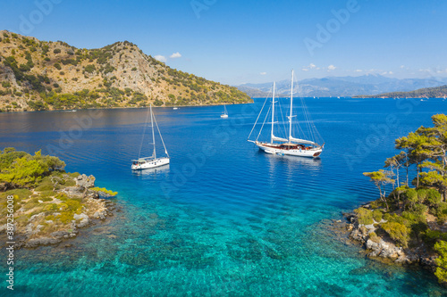 view to two yachts in emerald water between two cliffs under blue sky