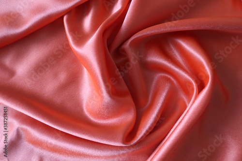 Smooth elegant coral silk or satin fabric. Draped luxury cloth texture for design. Close-up