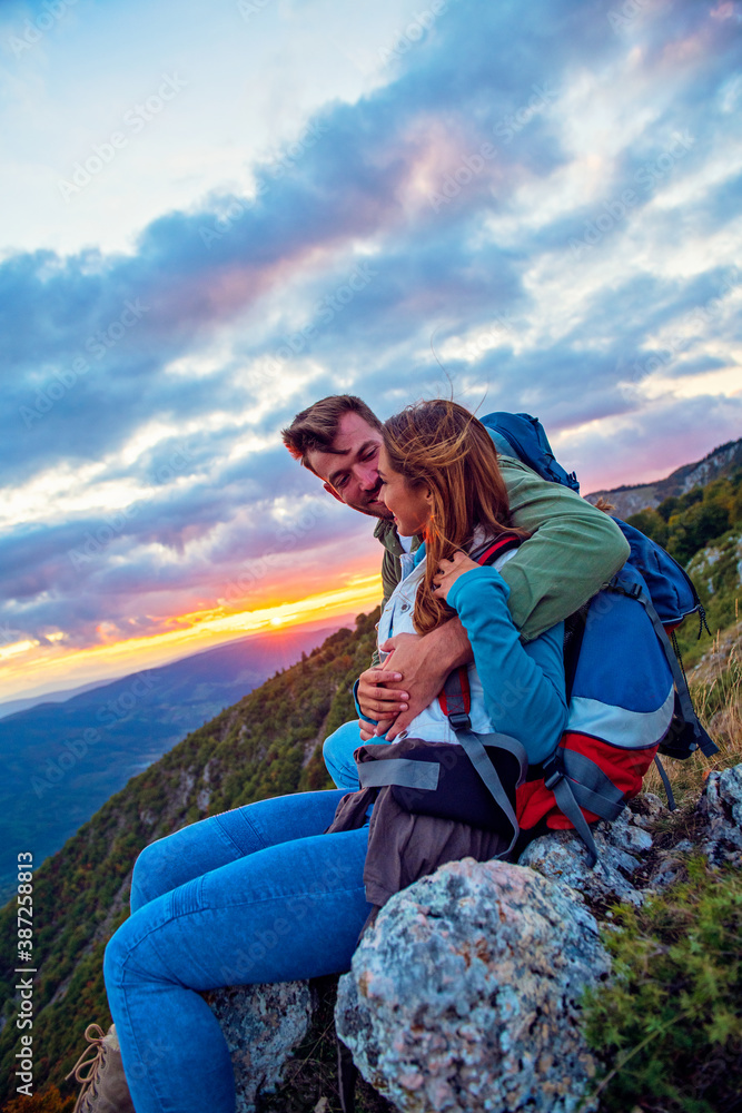 Young Couple Sitting On Top Of Mountain