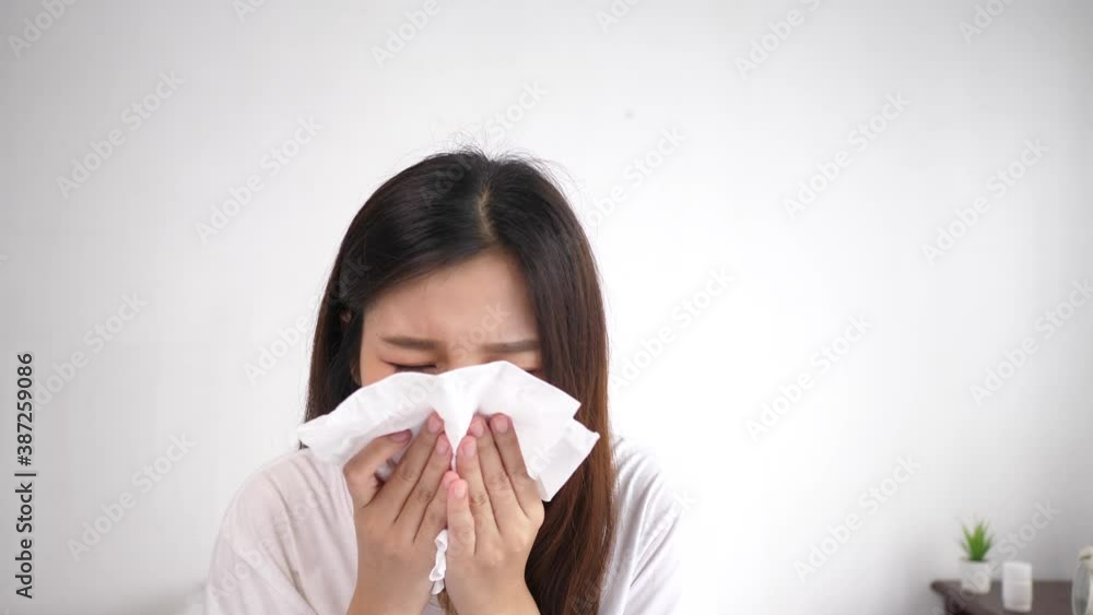 Asian young woman sneezes and wipes nose with tissue Asian young woman sneezes and wipes nose with tissue