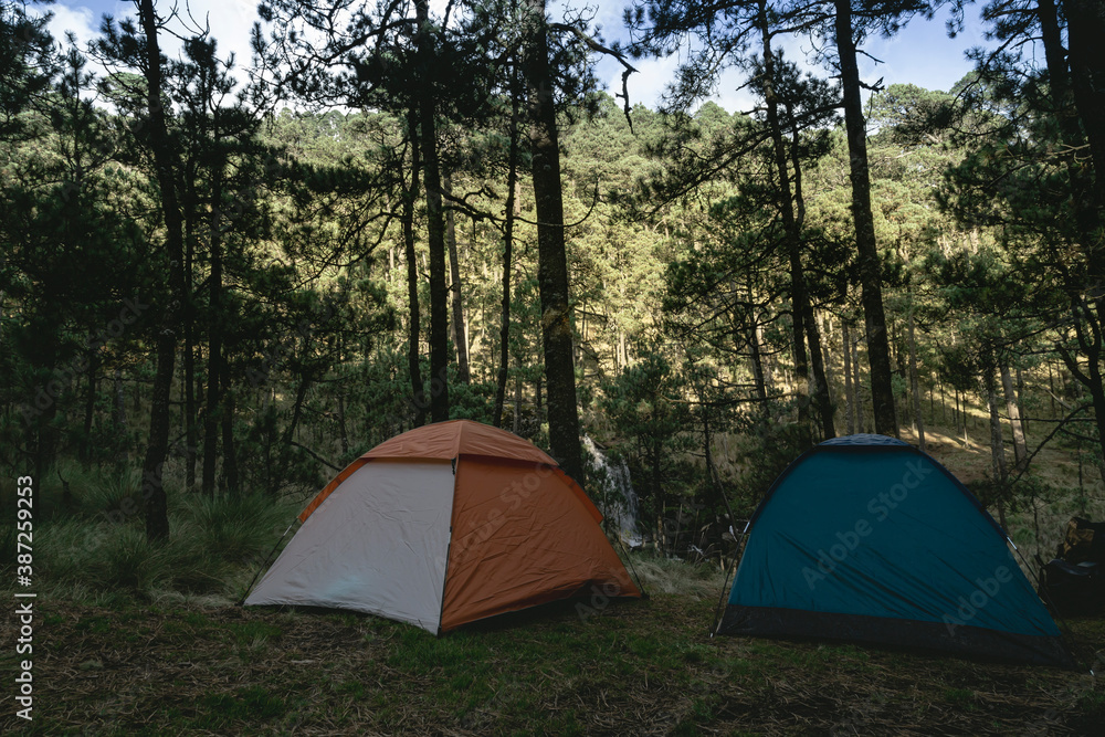 A tent stands camps at a shore of a waterfall for a wild camping, away from everything