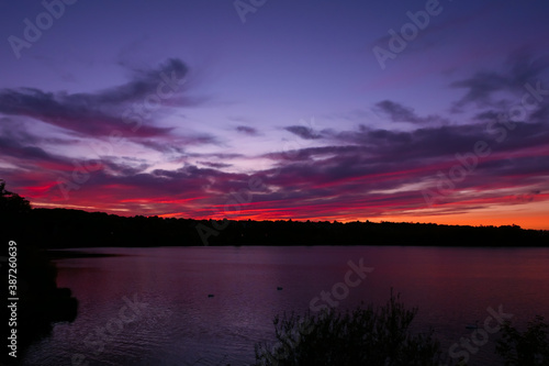 Amazing sunset over the water. Beautiful landscape with a lake and dramatic sky with cumulus clouds on the horizon.