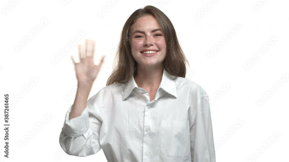 Video of pretty friendly woman saying hi, waving hand and smiling, greeting person, standing in white collar shirt Video of pretty friendly woman saying hi, waving hand and smiling, greeting person, standing in white collar shirt