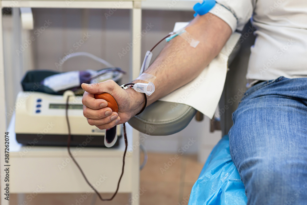 man donating blood from a vein for donation and squeezing a red ball. soft focus man donating blood from a vein for donation and squeezing a red ball. soft focus
