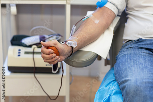 man donating blood from a vein for donation and squeezing a red ball. soft focus