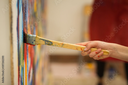 Closeup of the hand of a child painting a mural during an art lesson © Aubord Dulac