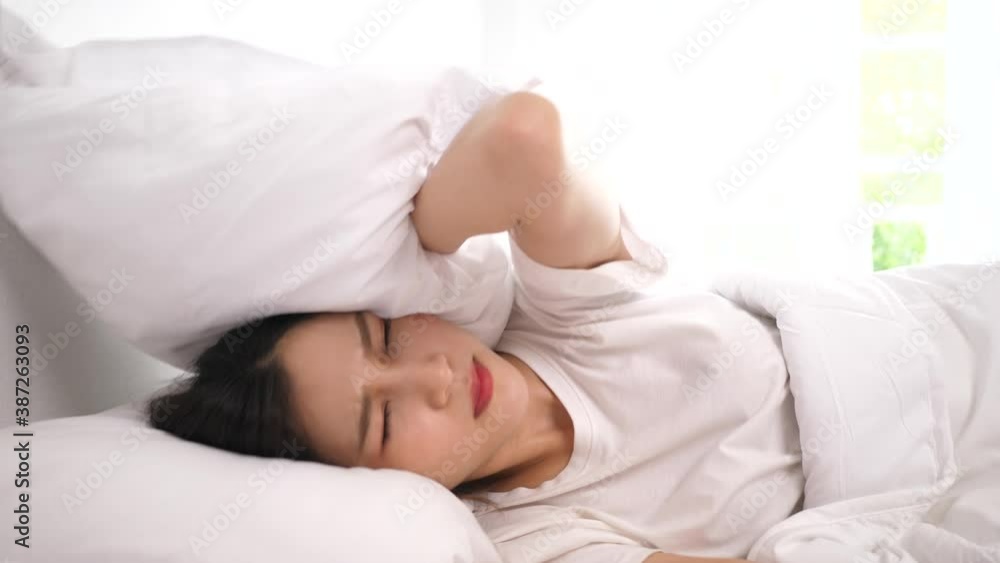 Asian young woman feeling slight anger with bad noisy room Asian young woman feeling slight anger with bad noisy room