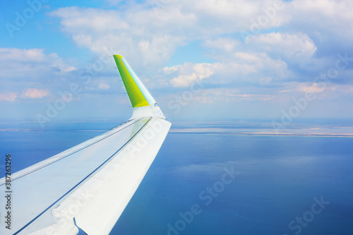 Airplane wing in the sky over the blue sea