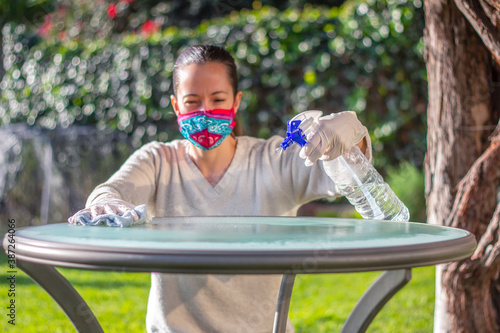 Mujer desinfectando con atomizador en jardín, covid. photo