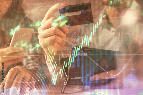 Double exposure of man and woman on-line shopping holding a credit card and forex graph hologram drawing. Stock market E-commerce pay on-line concept.