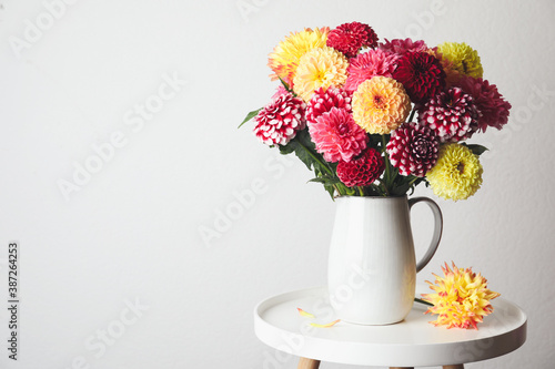 Bouquet of beautiful dahlia flowers on table near white wall. Space for text