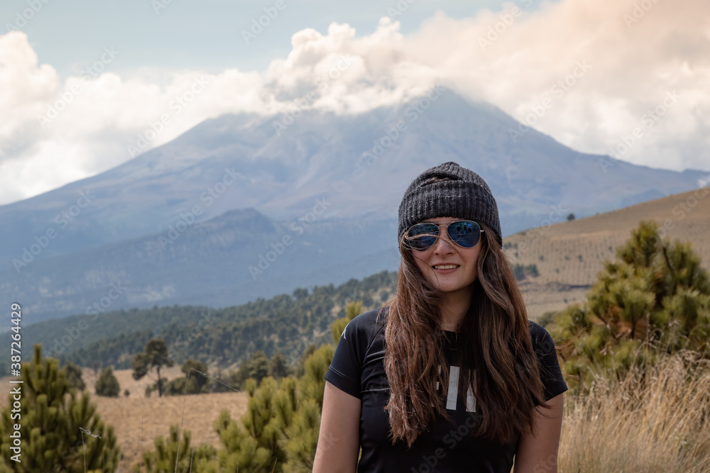 Young female hiker posing with a beautiful scene of the popocatepetl volcano behind