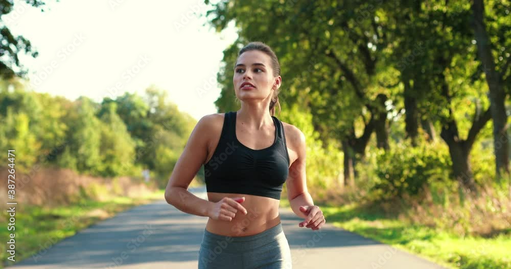 Portrait of fit Caucasian sportswoman in sportswear doing exercises for weight loss and running outdoor. Beautiful concentrated young female training. Sporty lifestyle. Workout concept Portrait of fit Caucasian sportswoman in sportswear doing exercises for weight loss and running outdoor. Beautiful concentrated young female training. Sporty lifestyle. Workout concept
