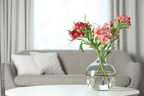 Vase with beautiful alstroemeria flowers on table in living room  space for text. Stylish element of interior design