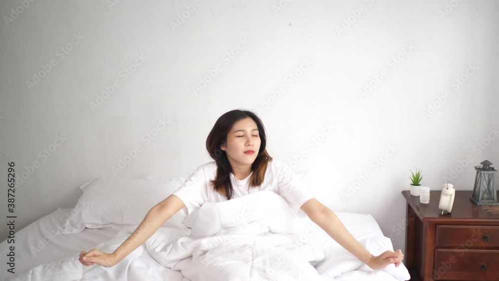 Pretty woman wake up and Stretches her arms in bedroom