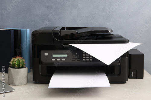 New modern printer on grey table at workplace photo