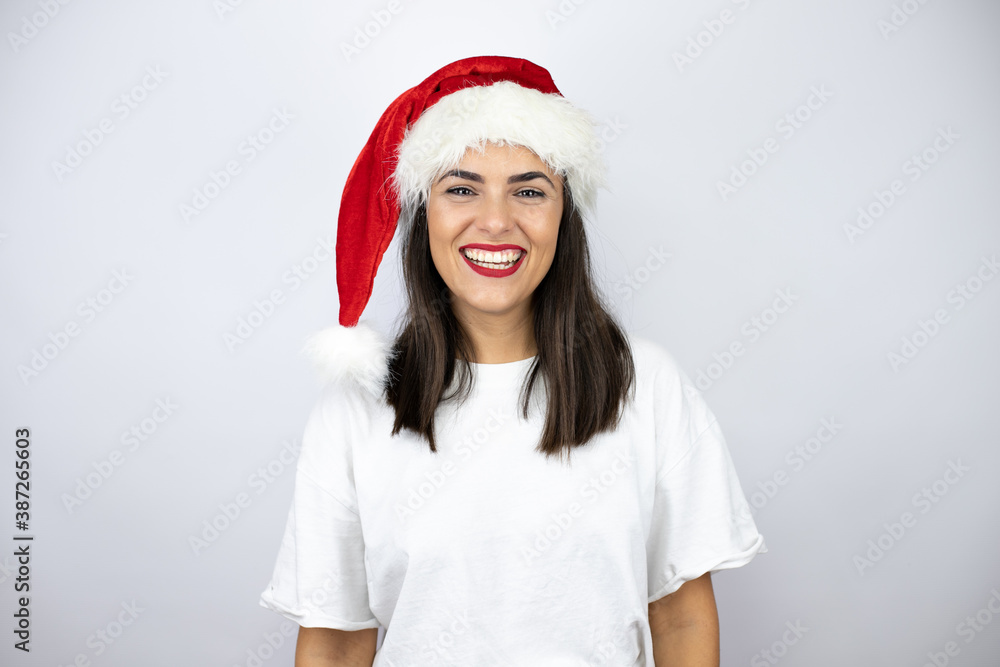Young beautiful woman wearing a christmas hat over white background very happy, smiling to the camera. Young beautiful woman wearing a christmas hat over white background very happy, smiling to the camera.