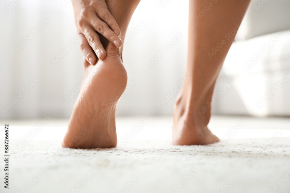 Young woman suffering from pain in foot indoors, closeup