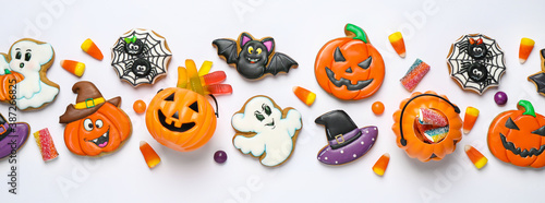 Tasty cookies and sweets for Halloween party on white table, flat lay