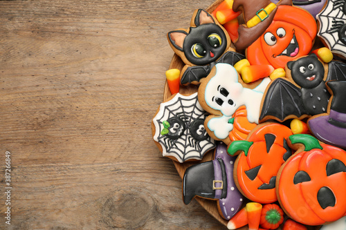 Tasty cookies and sweets for Halloween party on wooden table  top view. Space for text