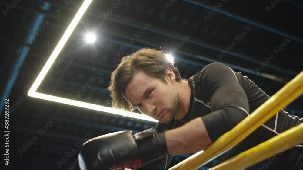 Aggressive male boxer screaming on boxing ring. Sport man having a break at gym Aggressive male boxer screaming on boxing ring. Sport man having a break at gym