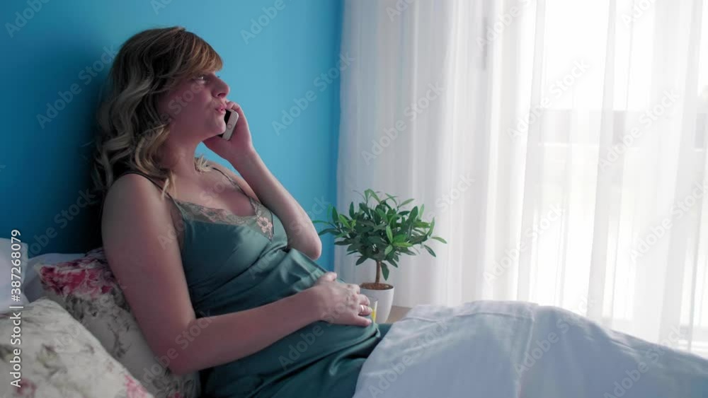 A pregnant woman in a semi-sitting position talking over her phone A pregnant woman in a semi-sitting position talking over her phone