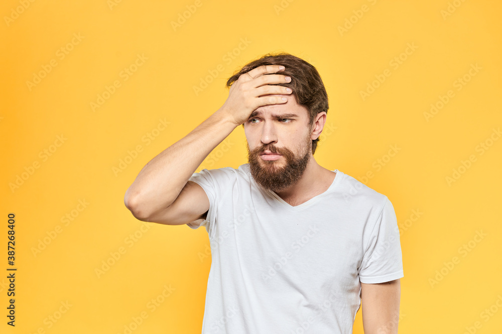 Bearded man in a white T-shirt gestures with his hands emotions studio yellow background Bearded man in a white T-shirt gestures with his hands emotions studio yellow background