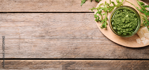 Top view of bowl with arugula pesto on wooden table, space for text. Banner design