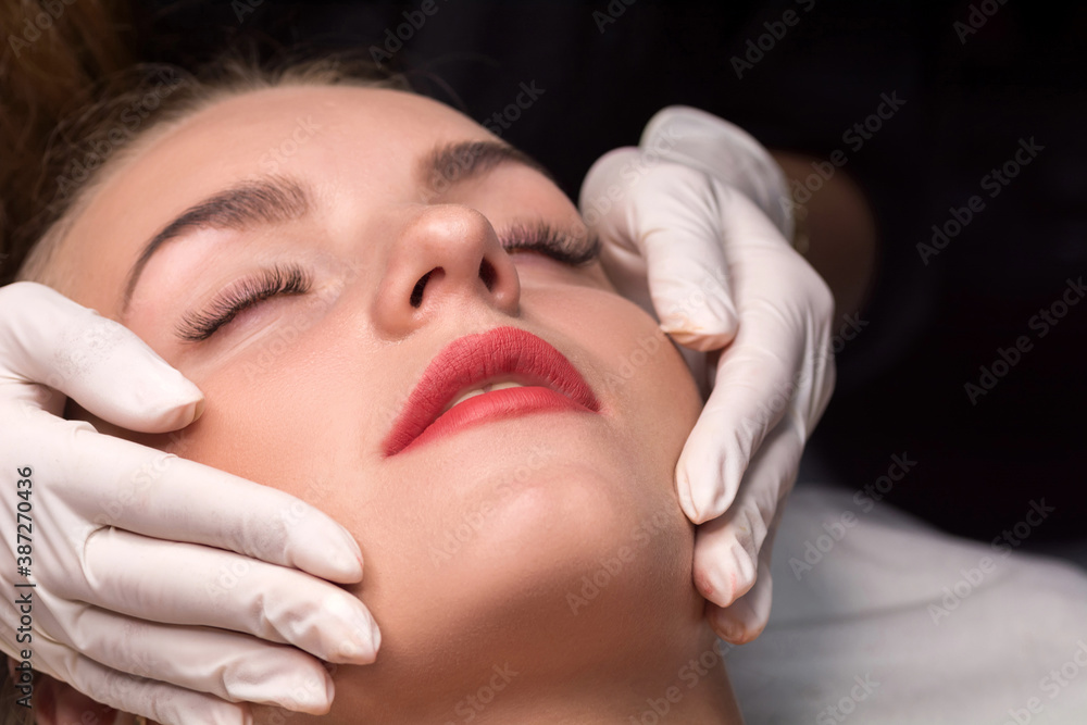 Young woman in a beauty salon. The beautician makes a facial cleansing procedure.