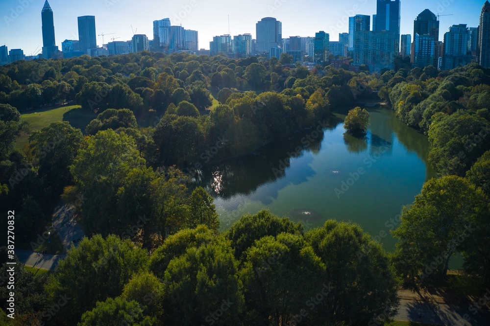 Obraz premium Panoramic aerial shot of the famous Piedmont park and Lake Clara meer with Atlanta skyline in background shot during golden hour by a drone