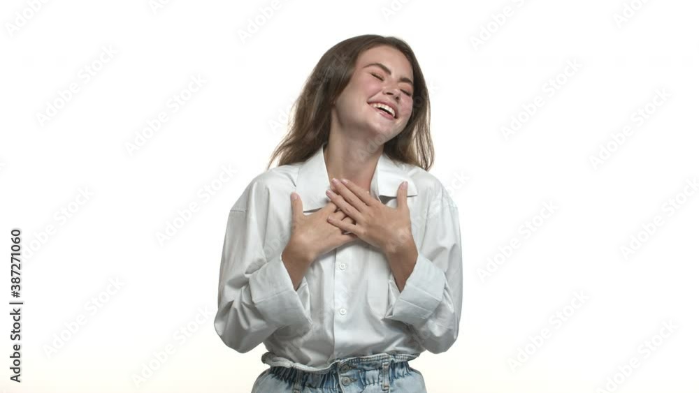 Happy attractive female model in white shirt, starting to laugh from something funny, standing over studio background Happy attractive female model in white shirt, starting to laugh from something funny, standing over studio background